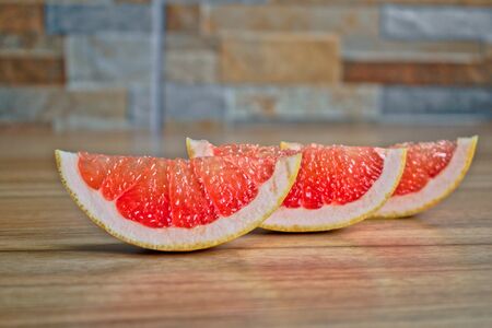 Closeup of a red grapefruit wedge on a wooden tableの写真素材