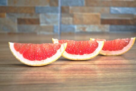 Closeup of red grapefruit wedges on a wooden tableの写真素材