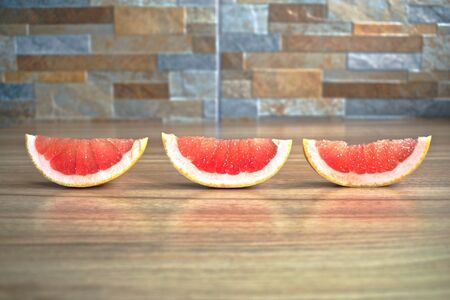 Closeup of red grapefruit wedges on a wooden tableの写真素材