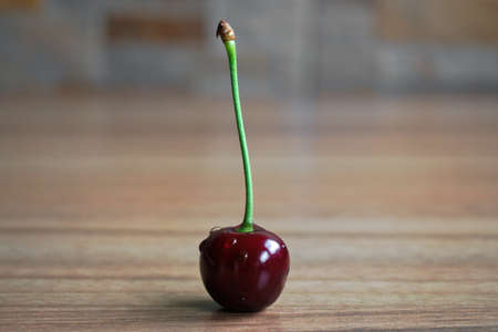 Closeup of a cherry on a wooden tableの写真素材