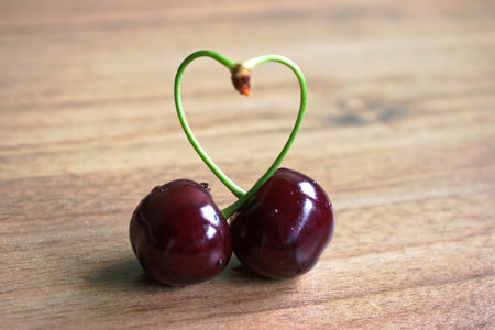 Closeup of cherries with a heart shaped stem on a wooden tableの写真素材