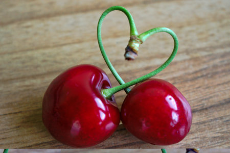 Cherries with a heart shaped stem on a wooden tableの写真素材