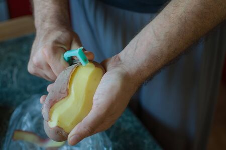 Closeup of hands peeling a potatoの写真素材