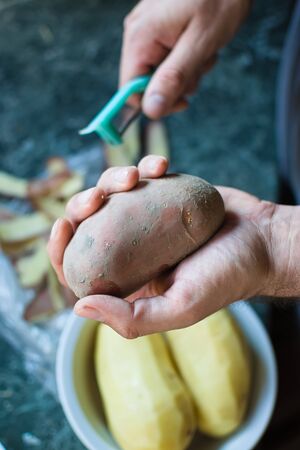 closeup of a hand holding a raw potatoの写真素材