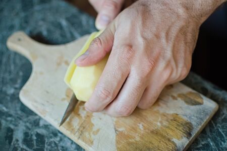 Closeup of a hand cutting a potato with a knifeの写真素材