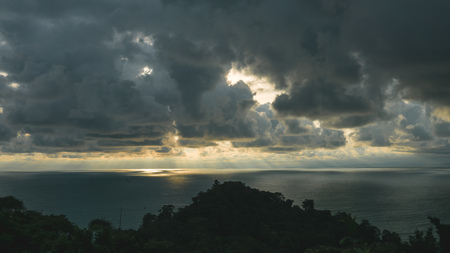 Sunrays comming through dark clouds over the seaの写真素材