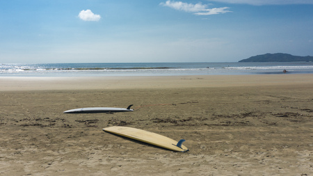 2 Surfboards on an empty sandy beach with small cloudsの写真素材