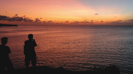 Man taking a photo of a beautiful pink tropical sunsetの写真素材