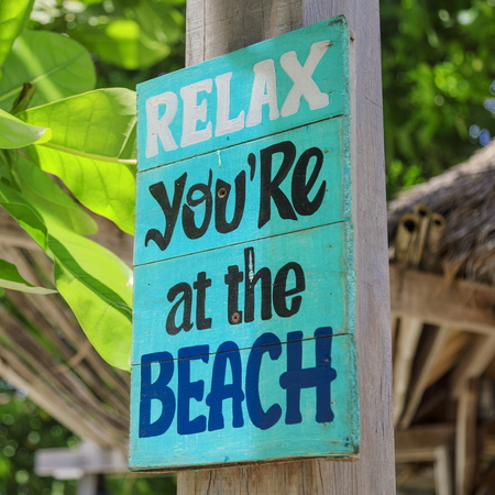 colorful wooden sign saying "Relax, you're at the beach". Enjoy your holidays in paradise on a tropical islandの写真素材