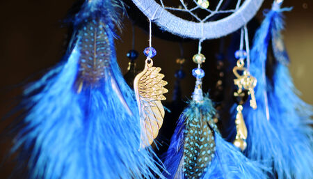 Blue dream catcher hanging on dark background close up with suspension wingの写真素材