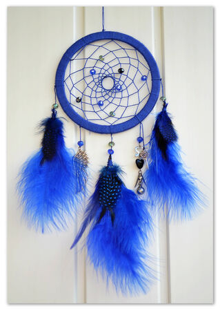 blue dreamcatcher on a light background with feathersの写真素材