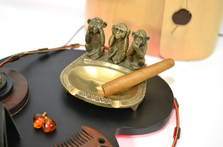 Copper ashtray with cigar and three monkeys and amber earringsの写真素材