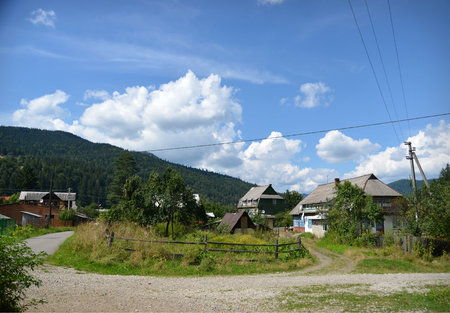 Summer view of the village on a background of mountains and blue skyの写真素材
