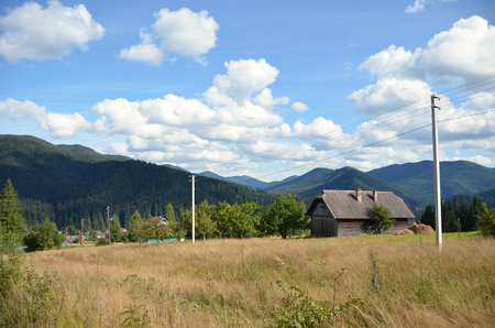 Countryside View with a small house on a background of mountains and blue skyの写真素材
