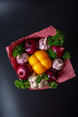 Unique festive bouquet of yellow peppers, red onions, garlic, mushrooms and parsley on a black background. Vegetable bouquet. Fruits and Vegetables of the Healthy Concept.の写真素材