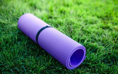 Close up Yoga mat roll on green grass ready for practice and relax with yoga, Recreation Conceptの写真素材