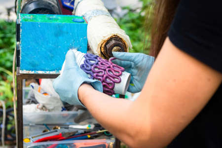Odessa, Ukraine. August 26, 2019: The process of creating stand for a glass made from recycled plastic. The molten plastic exits the plastic processing apparatus. girl creates based on a paper cupのeditorial素材
