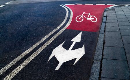 Bike path, dark road and white lines. Bicycle symbol in the evening. Sign of Cycling lane on open road track on city street.の写真素材