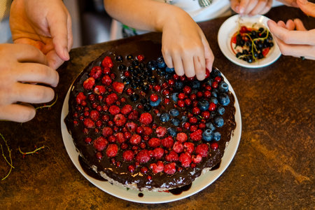 Decorating a chocolate cake with raspberries, blueberries and currants for the whole family. Close up. homemade.の写真素材