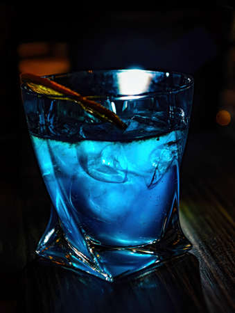 Cocktail on bar counter on bar background. Blue lagoon cocktail with blue curacao liqueur, vodka, lemon juice and soda, decorated with lemon slice.の写真素材