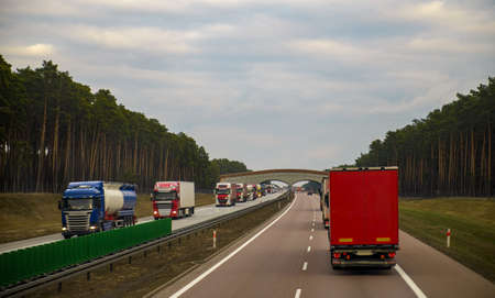 Trucks traveling on an asphalt highway between forests.の写真素材