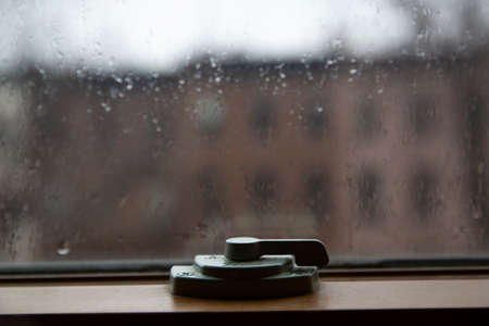 Close up of window latch. Window hasp. Rain drops on a glass.の写真素材