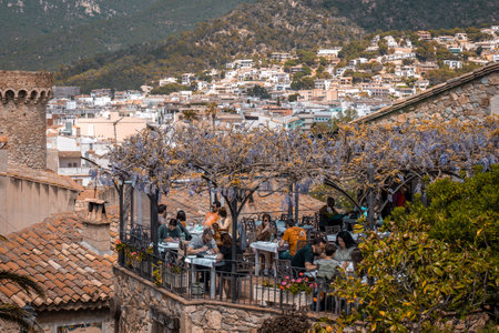 Barcelona, Spain - April 16, 2022: Old town of Tossa de Mar in Spain with rooftop restaurant and people eating. Outdoor dining in natureのeditorial素材