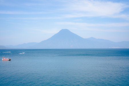 View of boats and volcano in the distance seen from the Lake Atitlan surface in Guatemalaの写真素材