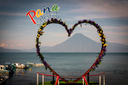 Heart shaped spot for photo taking with Pana your destination sign in lake atitlan and volcano in the distance in Panajachel, Guatemalaの写真素材