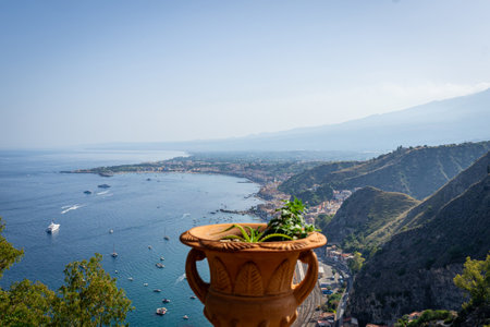 Decorative clay Amphora pot with succulent plants with Taormina aerial view in the backgroundの写真素材