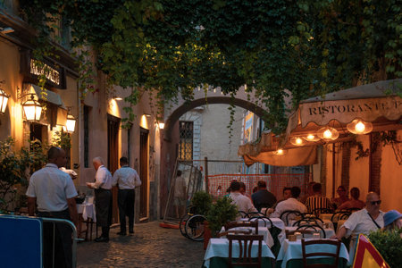 Rome, Italy - August 15 2023: Restaurant with outdoor seating at evening. Waiters serving food outsideのeditorial素材