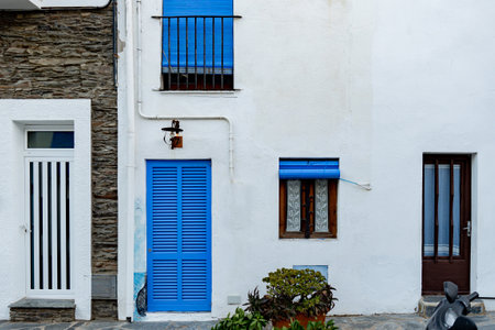 facade of a residential building with white walls, doors and window with blue shuttersの写真素材