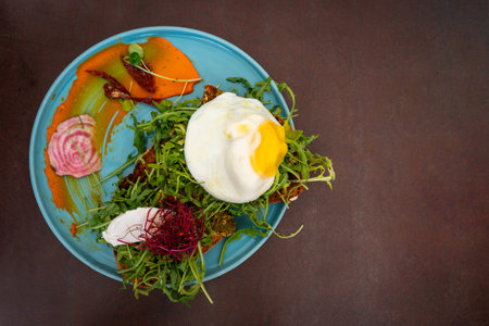Plate with poached egg served on greens with side of dressingの写真素材
