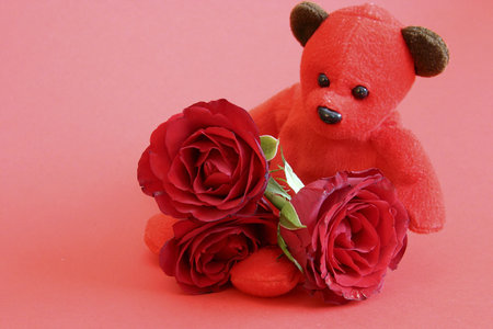 red teddy bear with roses on red backgroundの写真素材