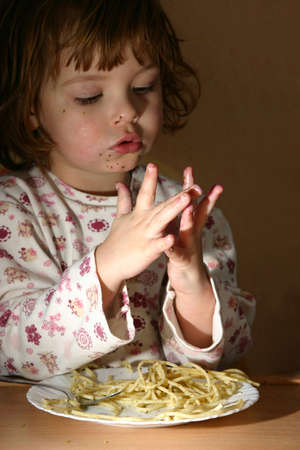 little cute girl eating spaghetti with pesto sauceの写真素材