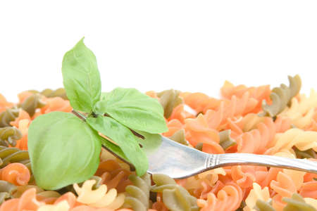 fresh basil leaves and fork on colorful pastaの写真素材