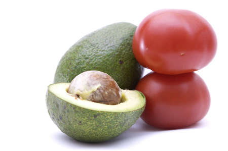 composition of tomato and cut by half avocado isolated on whiteの写真素材