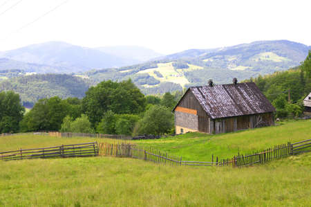landscape with green grass, building and mountains in a horizon, vivid colorsの写真素材