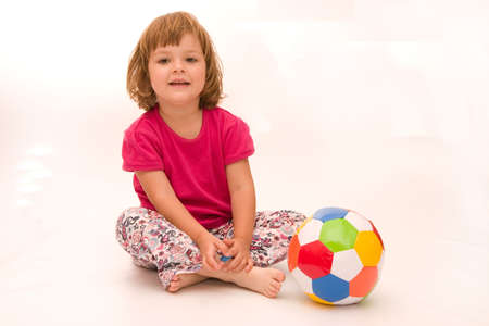 little, cute girl with colorful football isolated on whiteの写真素材