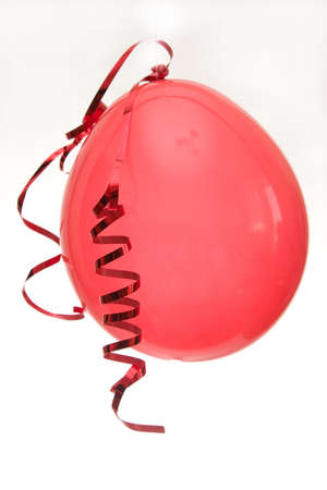 red balloon with twisted ribbon isolated on whiteの写真素材