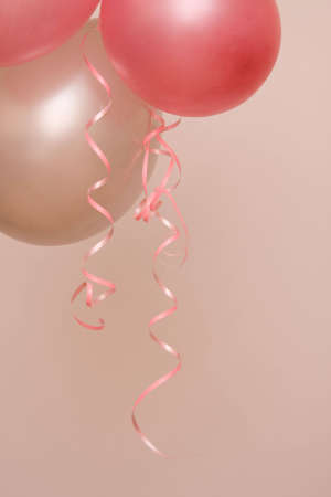 decorative party balloons with ribbons on pink backgroundの写真素材