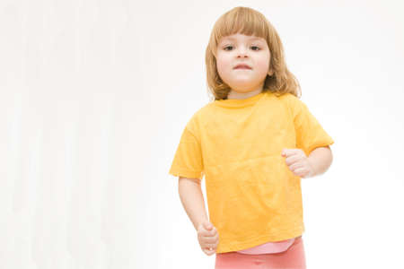 little girl in yellow shirt running isolated on whiteの写真素材