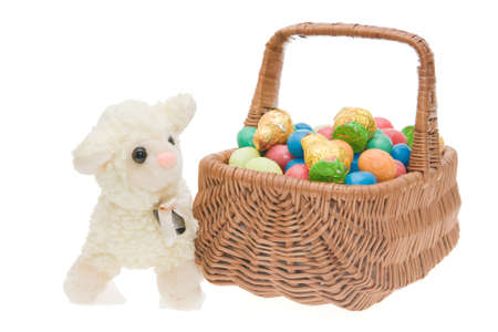 Easter sweets for children in a wicker basket, isolated on whiteの写真素材