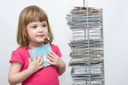 little girl choosing compact disc with her favourite musicの写真素材