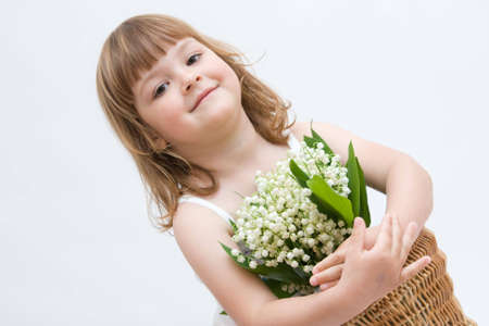 little, pretty girl holding bunch of lilies of the valley on white backgroundの写真素材