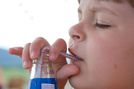 little, cute girl drinking with a strawの写真素材