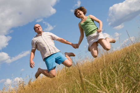 happy couple jumping together on a summer dayの写真素材