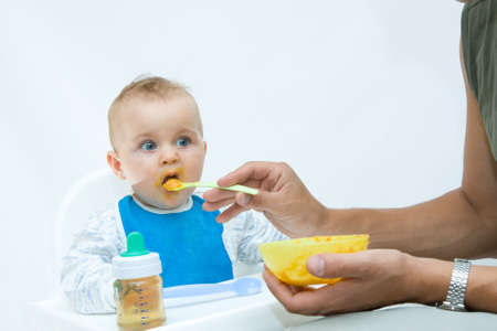man feeding baby with a spoon, on bright backgroundの写真素材