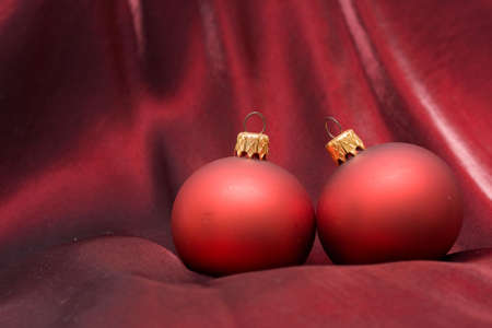 two red Christmas baubles on purple backgroundの写真素材