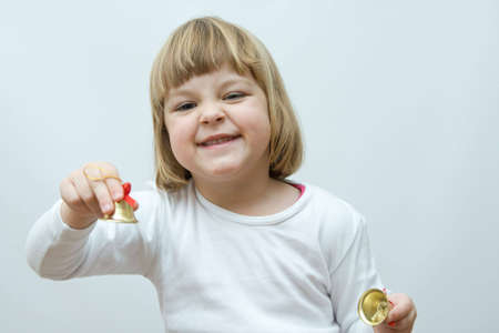 little, cute girl playing with golden Christmas bellsの写真素材